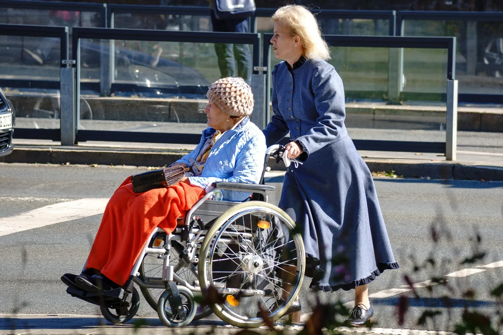 A caregiver walking outdoors with a loved one who uses a wheelchair